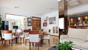 Un vestíbulo de hotel con un área de comedor, un bar y un espacio de estar con un sofá y una mesa de centro.