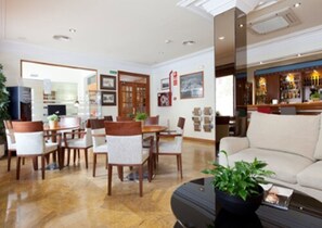 Welcome to our hotel lobby, featuring a spacious reception area with a comfortable seating space and a beautiful potted plant.