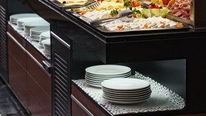A buffet with various food items and plates.