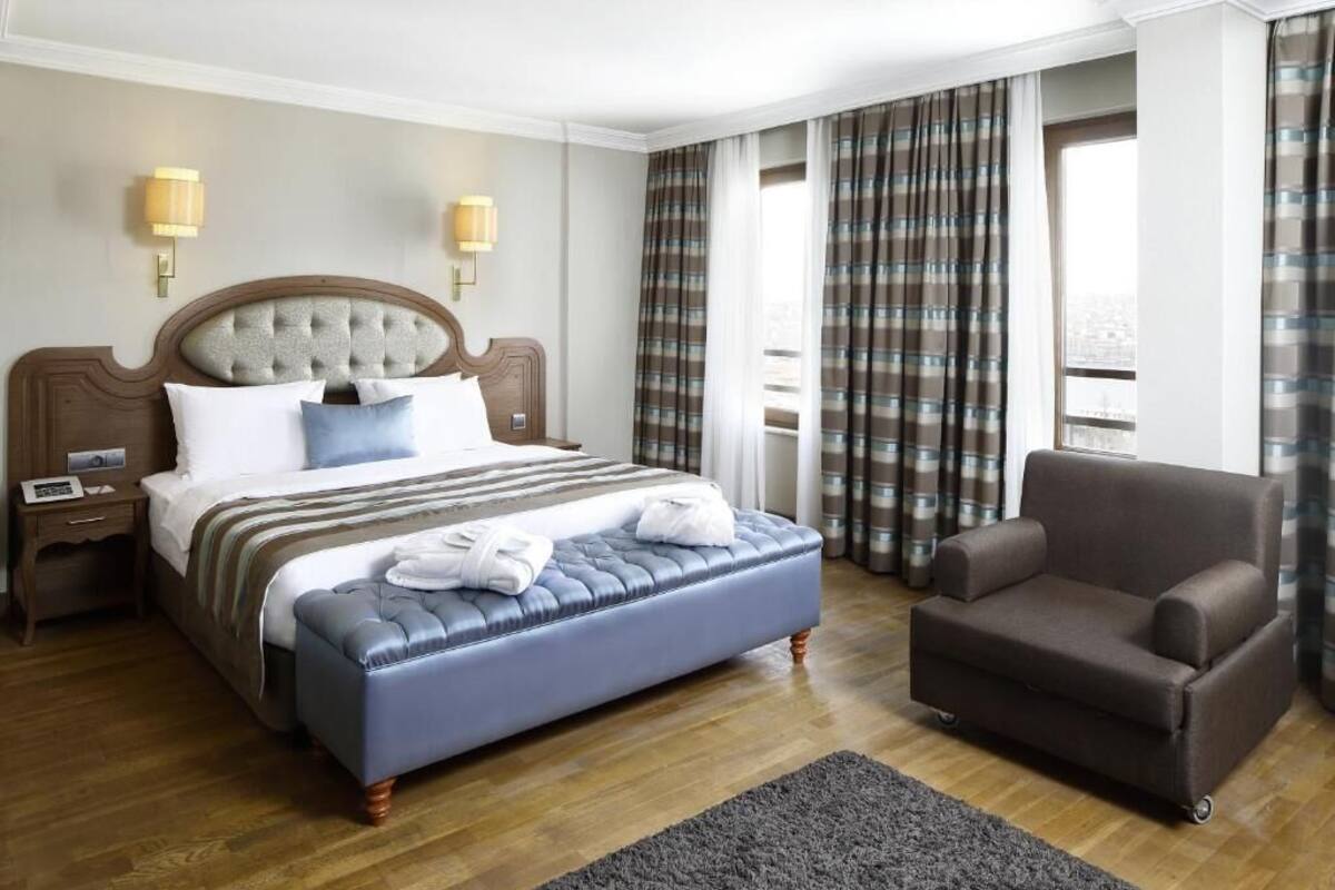 Una habitación de hotel con una cama grande, un sofá y una mesita de noche.