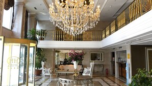 A grand lobby with a large chandelier, a central seating area, and a decorative floor pattern.