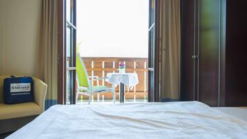 Ein Hotelzimmer mit Bett, Stuhl, Tisch und Blick ins Freie.