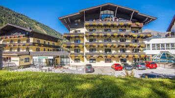 Ein mehrstöckiges Hotel mit Balkonen, einem Schild mit der Aufschrift „BÄRENHOF“ und einem Parkplatz mit mehreren Autos.