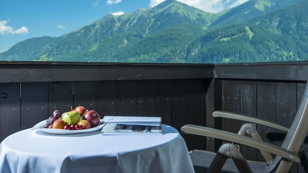 Ein Tisch mit Obstplatte und Buch, ein Stuhl und Blick auf Berge.