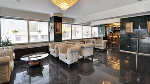 Un hall d’entrée spacieux, agrémenté d’un lustre, de grandes fenêtres et de fauteuils confortables.
