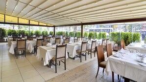Un restaurant avec une terrasse, des tables recouvertes de nappes blanches et des chaises.