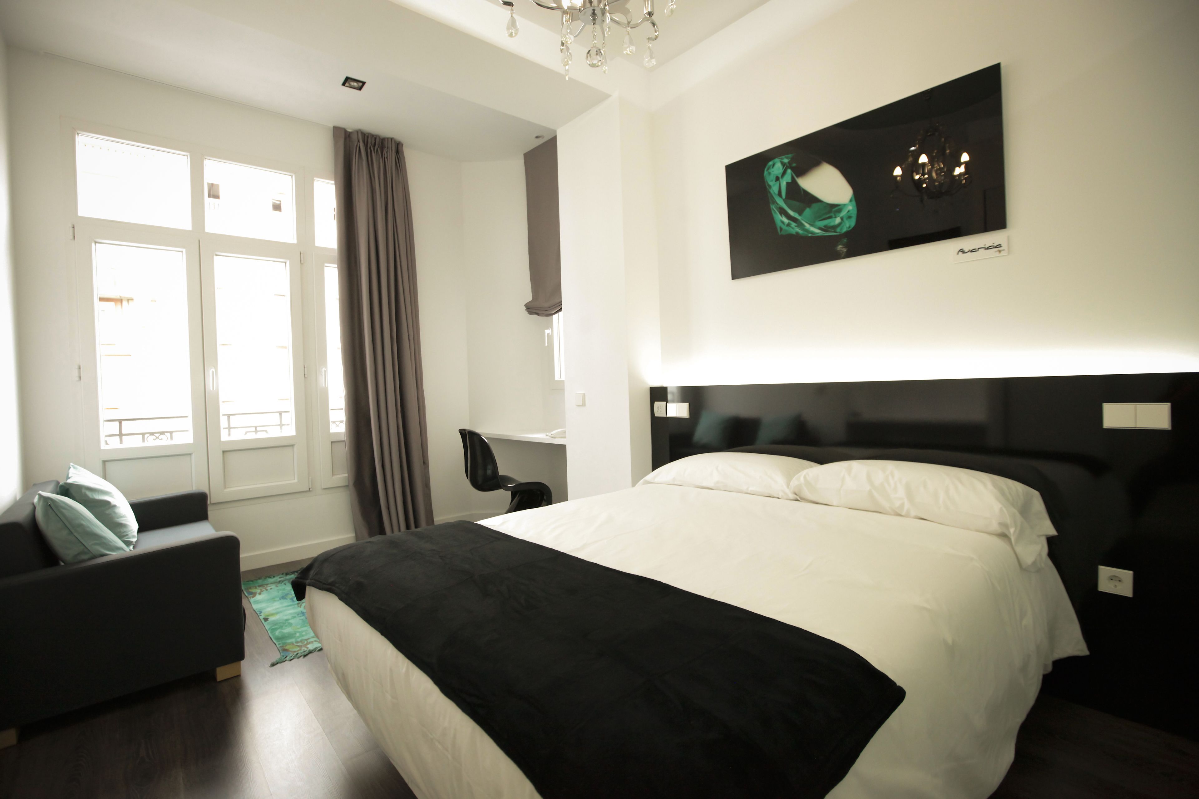 A hotel room with a large bed, a sofa, a chair, and a window with curtains.
