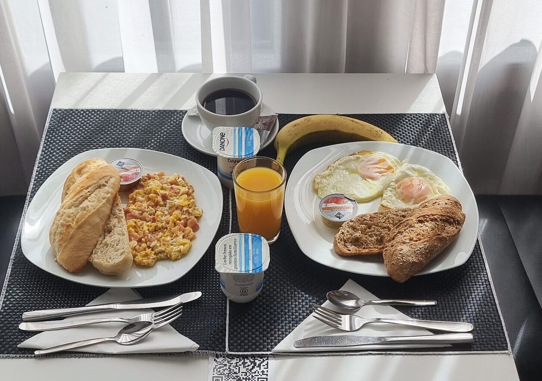 Egy asztalon tálalva: rántotta, pirítós, egy croissant, egy banán, egy csésze kávé és egy pohár narancslé – egy tipikus reggeli.