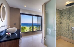 A modern bathroom with a large window, a glass shower enclosure, and a white sink with a flower vase.