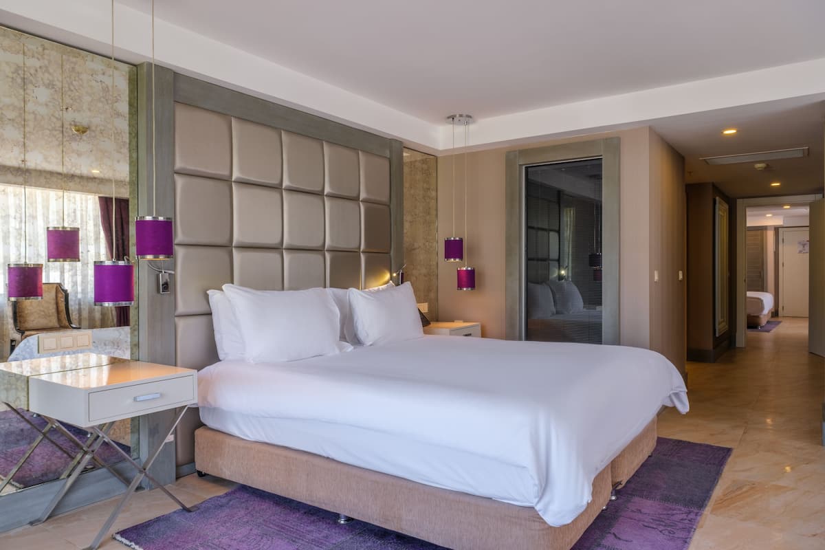 A modern hotel room with a large bed, a desk, and a seating area.
