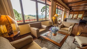 Un vaste espace de vie agrémenté d’une grande fenêtre offrant une vue panoramique, d’une table basse en bois et de sièges confortables.