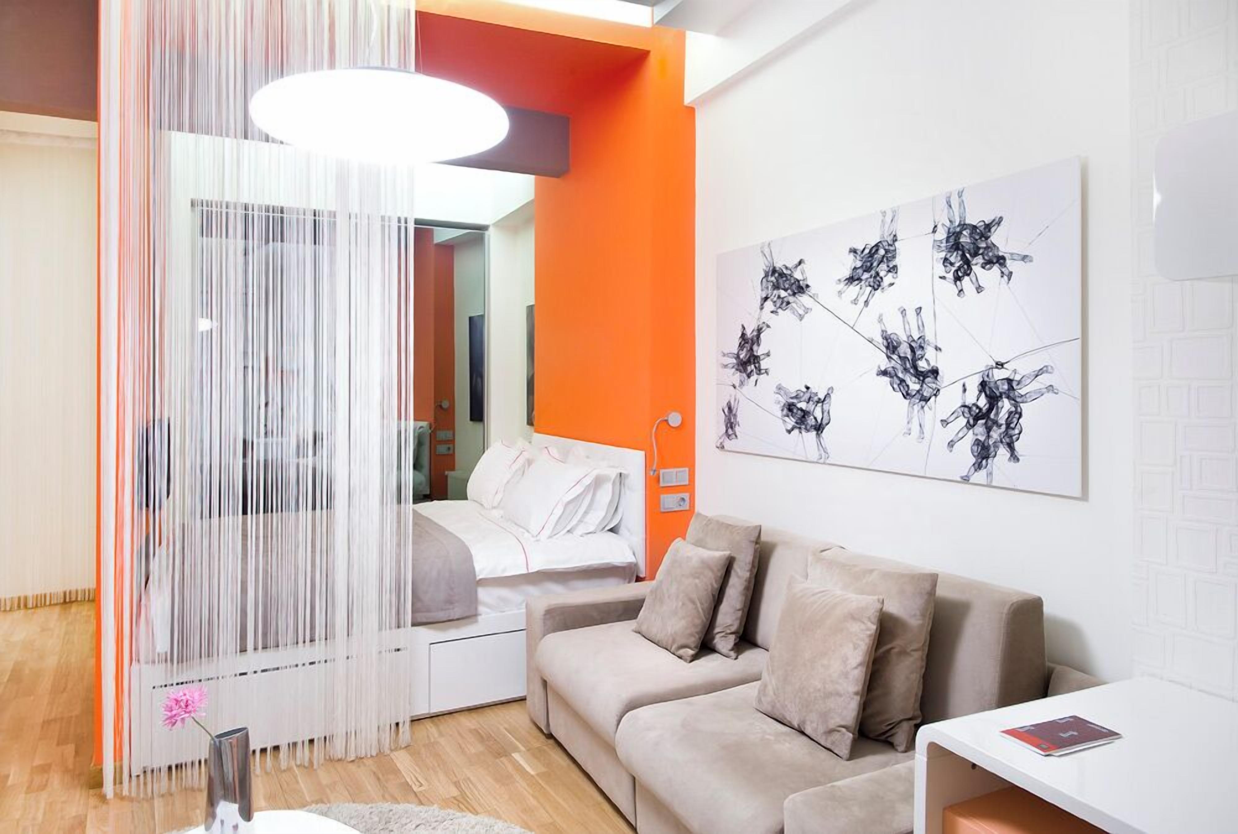 A modern living room with a sofa, a white coffee table, and a painting on the wall.
