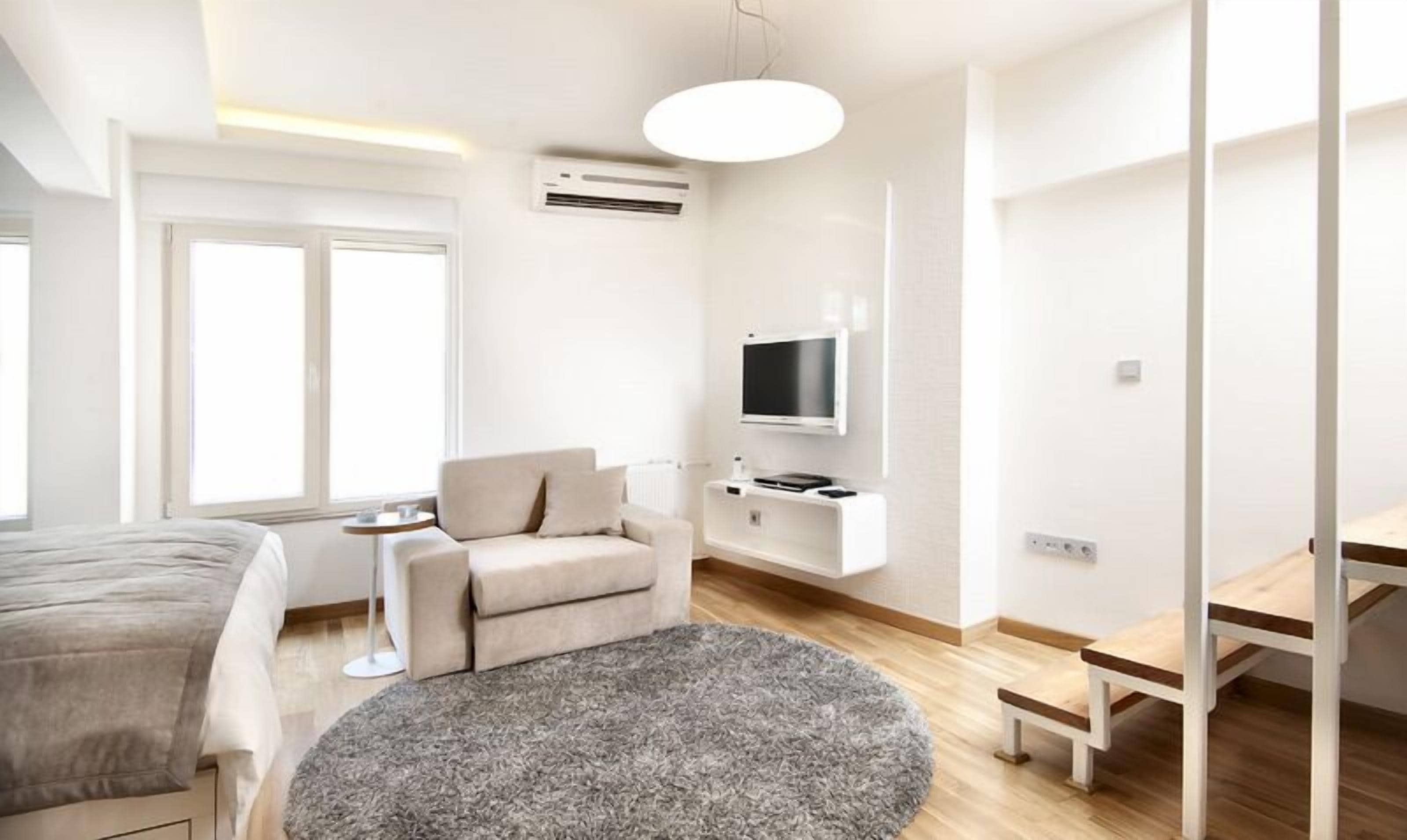Een moderne hotelkamer met een bed, een bank, een televisie en een kleine tafel.
