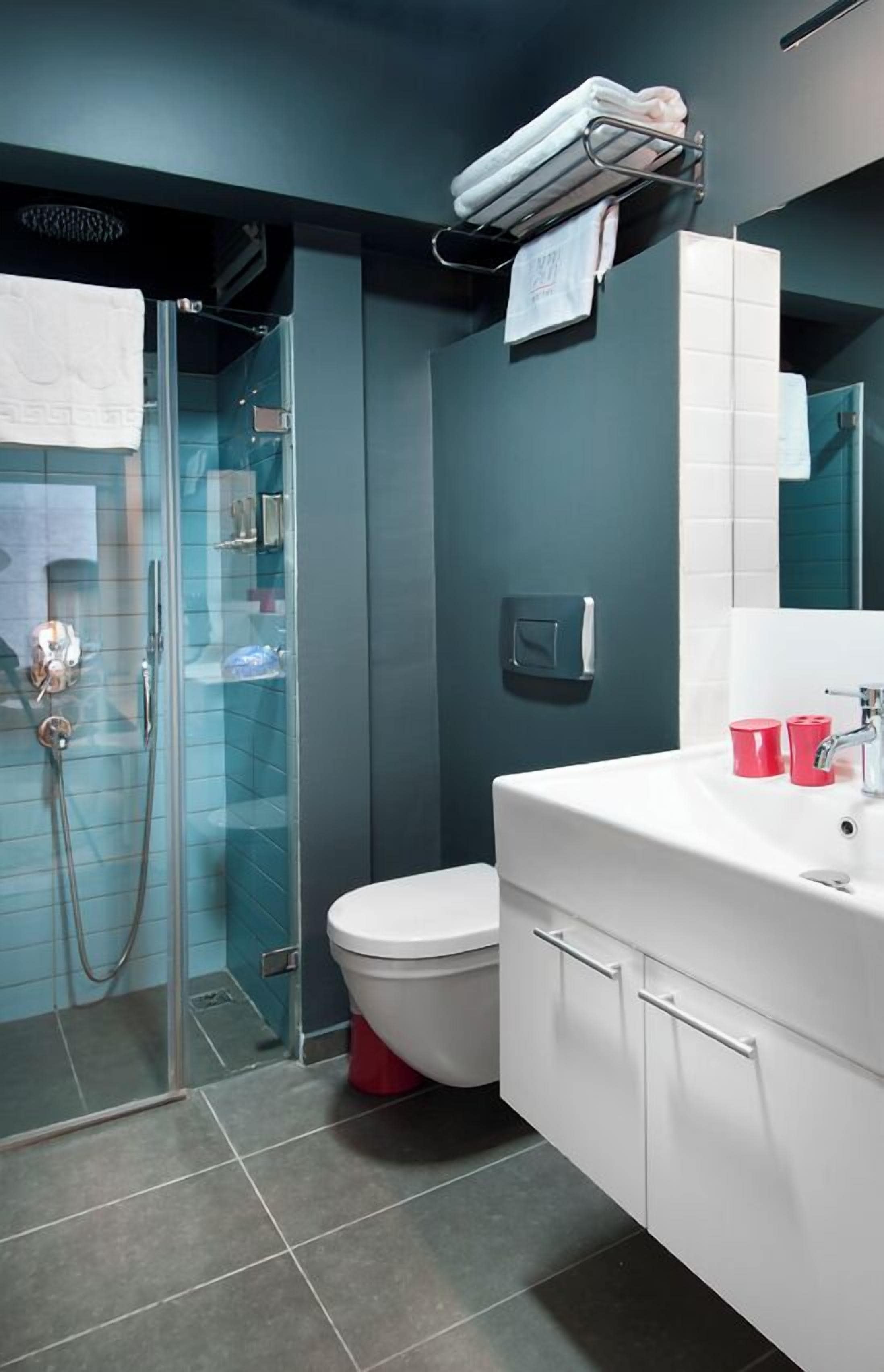 A modern bathroom with a glass shower enclosure, a white toilet, and a white sink with a mirror.