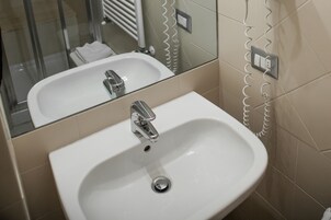 Un bagno con lavandino bianco, specchio e zona doccia.