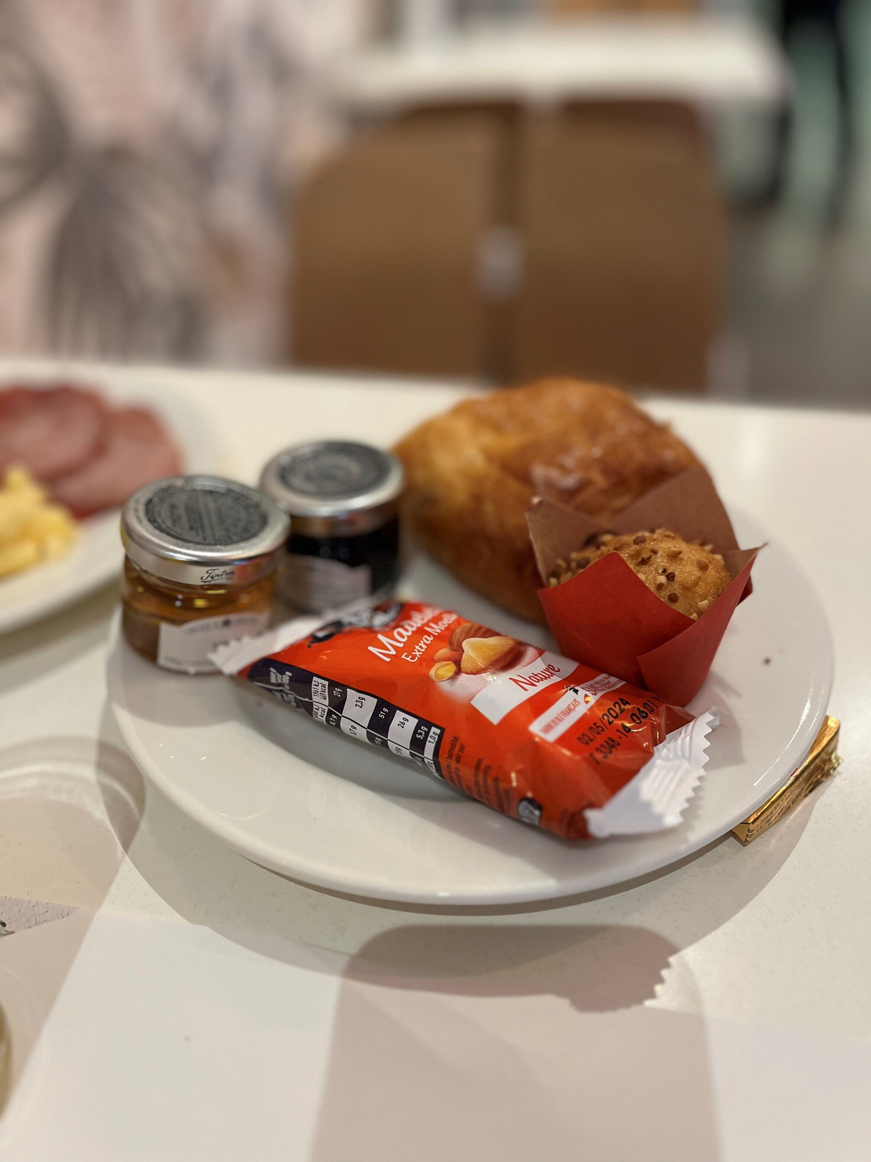 Un plat amb un croissant, un envasament de Nutella i dos pots de melmelada.