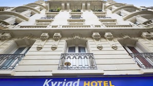 Fachada de hotel con arquitectura clásica, que incluye balcones ornamentados y un letrero destacado que dice "Kyriad HOTEL".