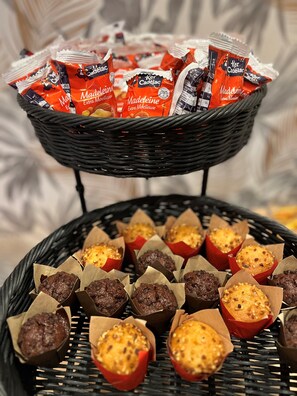 A basket containing packets of Cadelac chocolate and a tray of assorted baked goods. - Kyriad Paris 18 - Porte de Clignancourt - Montmartre (Paris)