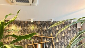 Una sala de estar moderna con papel tapiz estampado, una estantería de madera y plantas verdes.