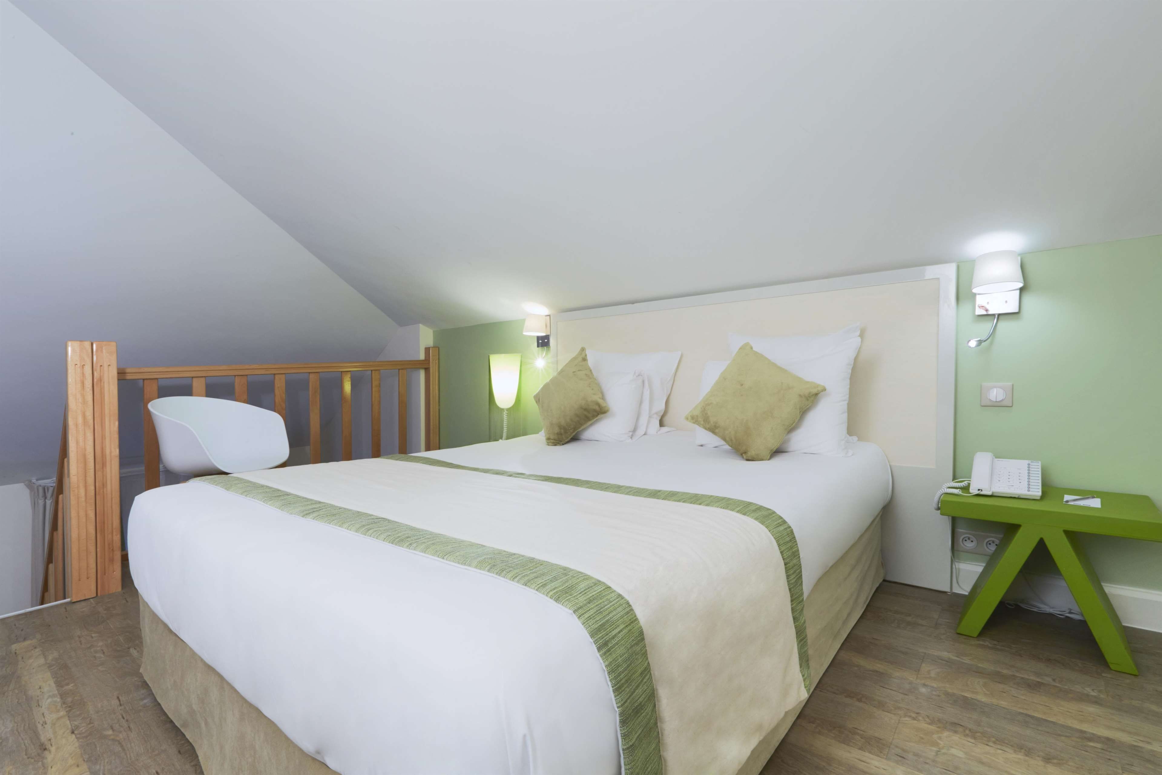 Un dormitorio con cama, mesita de noche, silla y baranda de madera.