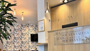 Un mostrador de recepción moderno con un cartel en francés, un mueble de madera y una planta sobre una mesa.