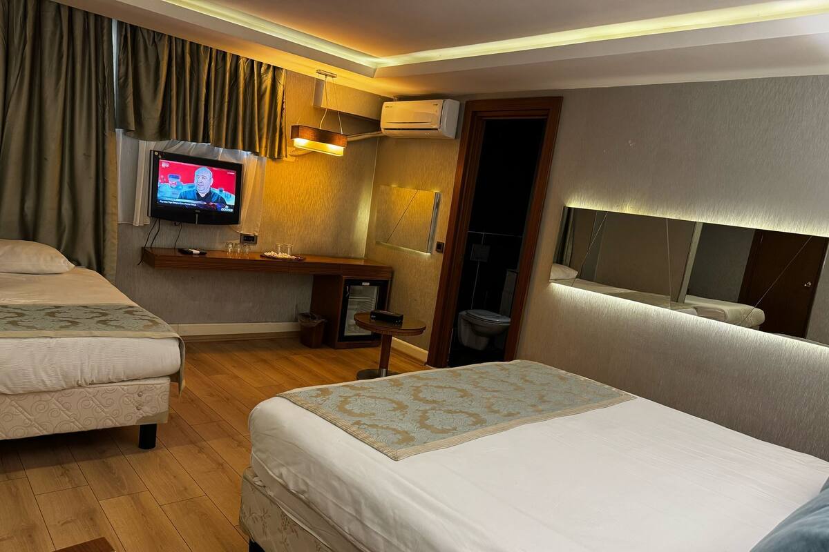 A hotel room with two beds, a television, a small table, and a mirror.