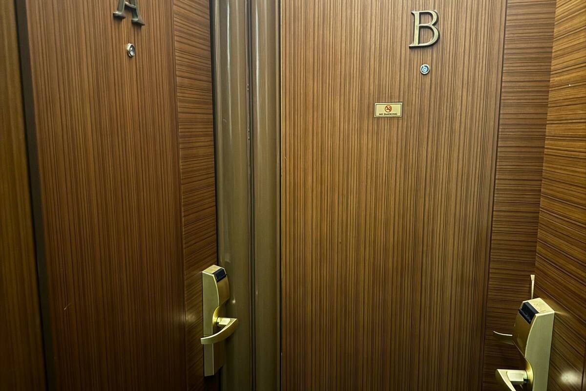 A wooden elevator with doors labeled A and B, equipped with modern handles and a no-smoking sign.