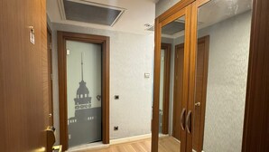 A hallway with wooden flooring, a glass door with a view of a building, and a ceiling vent. - Style Star Hotel Cihangir (Istanbul)