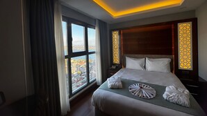 A hotel room with a large bed, a nightstand, a window with a view of the city, and a ceiling with a yellow light strip. - Style Star Hotel Cihangir (Istanbul)