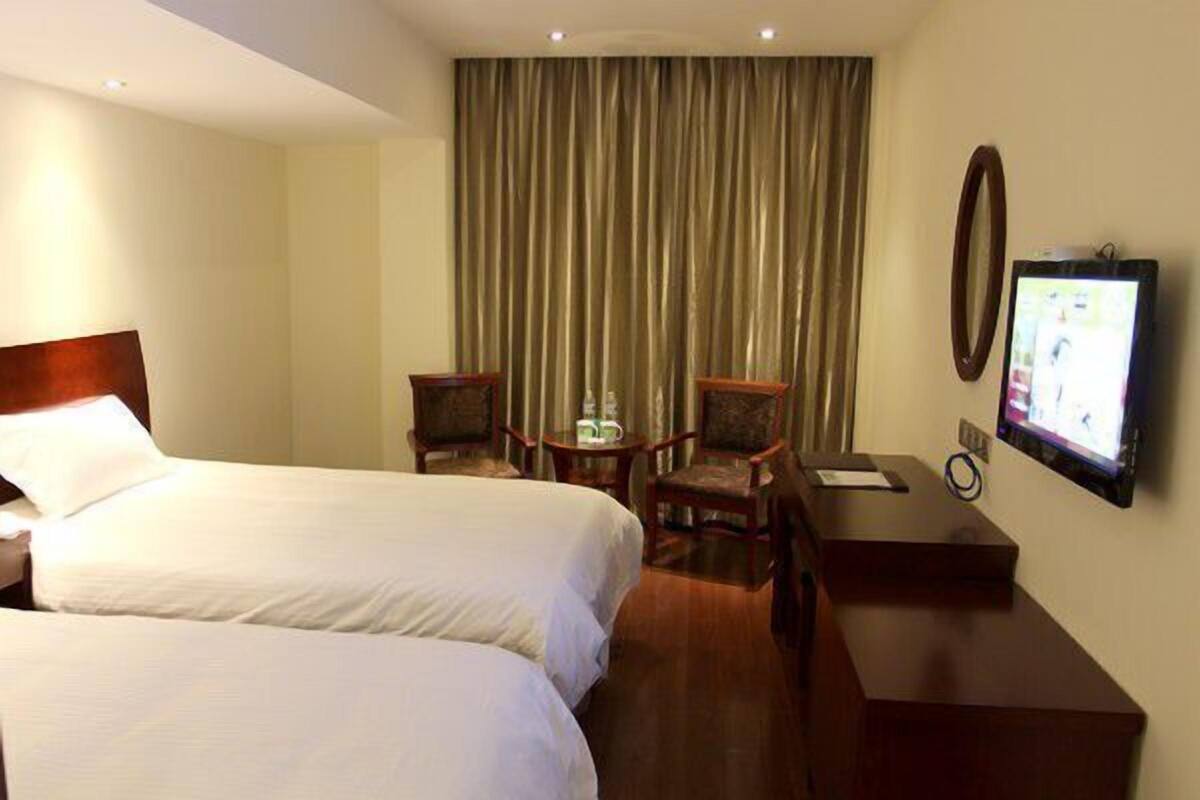 Ein Hotelzimmer mit zwei Betten, einem Schreibtisch, einem Fernseher und einem Vorhang.
