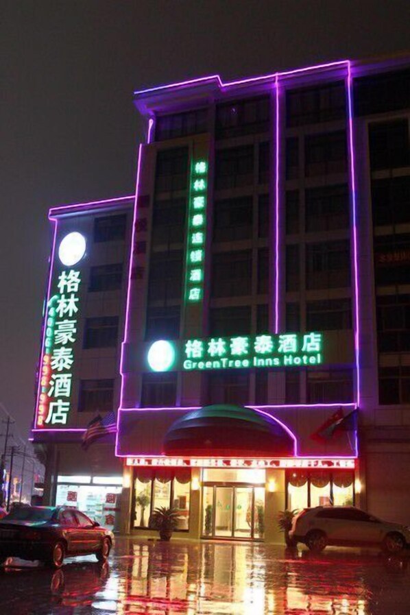 Un hôtel doté d’une enseigne lumineuse au néon, comprenant les inscriptions « GreenTree Inns Hotel » et « GreenTree Inn Hotel ».