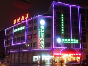 Un hôtel avec une enseigne lumineuse au néon, plusieurs étages et une entrée bien visible.