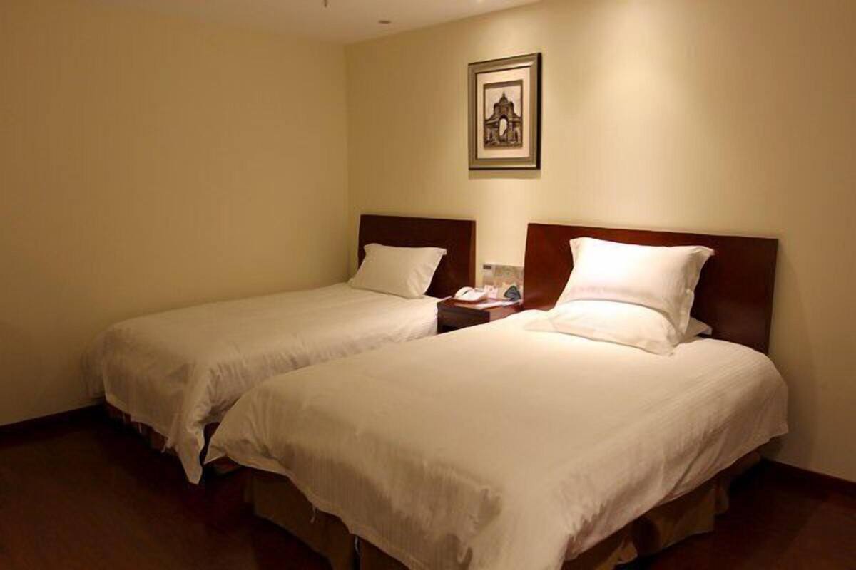 Zwei Einzelbetten mit Holz Kopfteilen in einem Hotelzimmer.