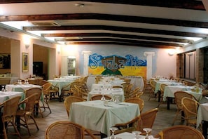 A restaurant with multiple tables and wicker chairs, a mural on the wall, and a tiled floor. - Hotel Residence Sciabache (Zambrone)