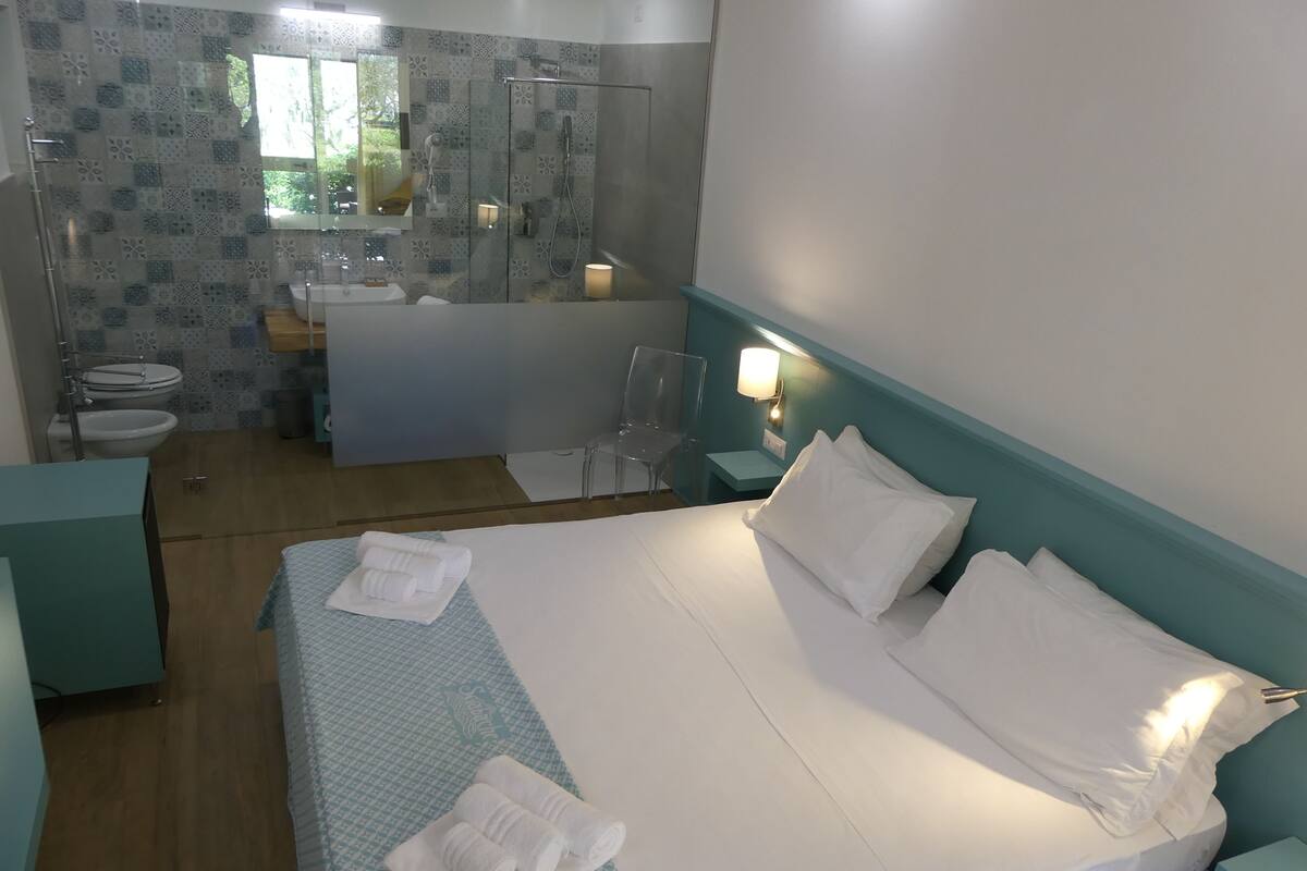 Ett hotellrum med en säng, ett badrum och en dusch.