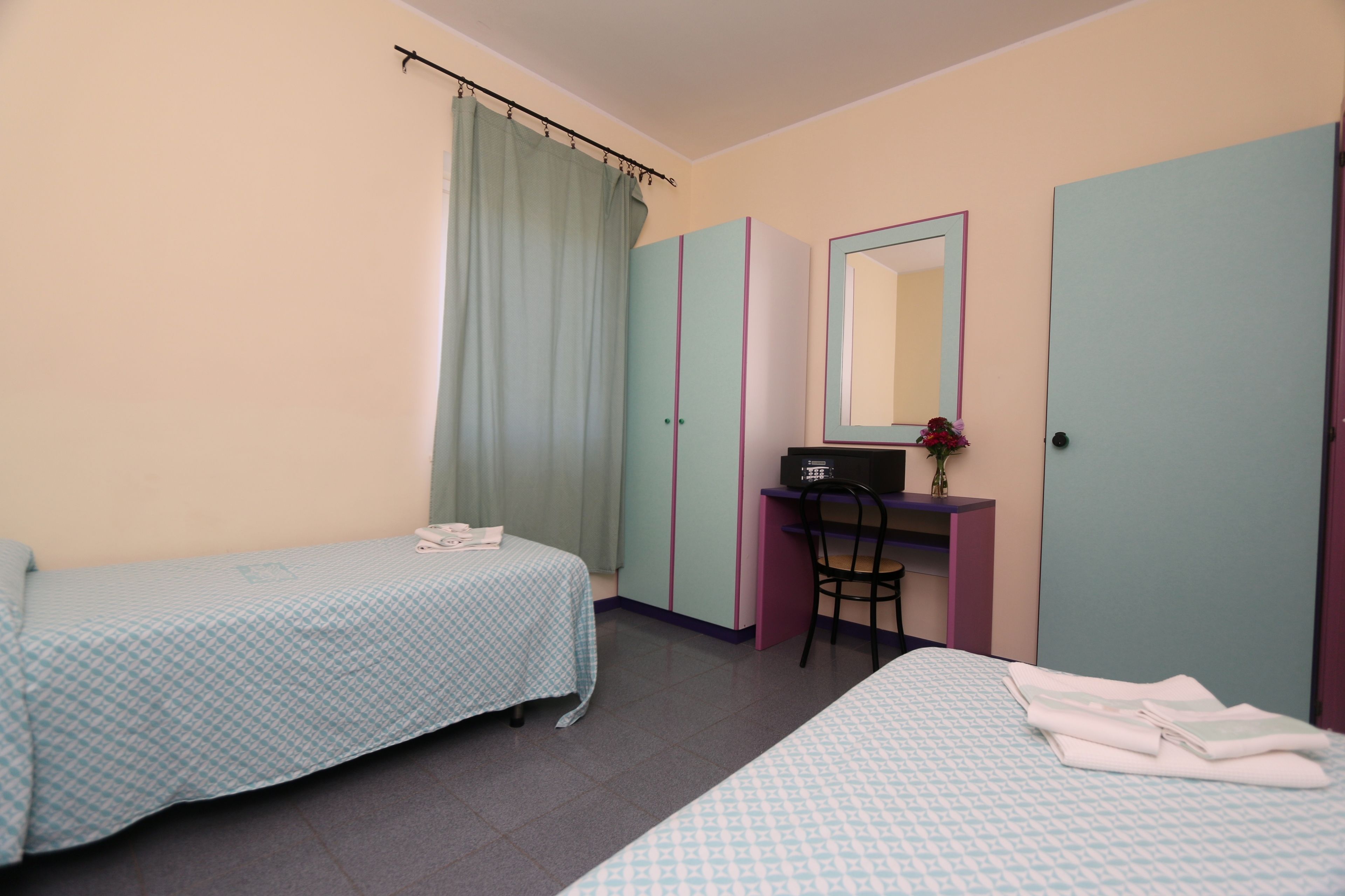 Un dormitorio con dos camas, un escritorio y un espejo.
