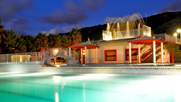 Une piscine dotée d’une zone couverte et un bâtiment avec un toit rouge.