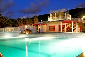 A swimming pool with a covered area and a building with a red roof. - Hotel Residence Sciabache (Zambrone)