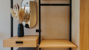 Une pièce au décor minimaliste, avec un bureau en bois, un miroir et un vase contenant des plumes d’herbe des pampas.