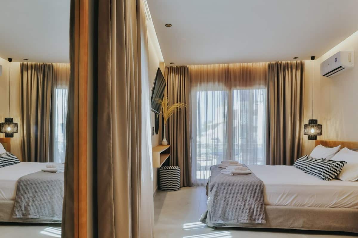 Quarto de hotel com duas camas, um espelho grande e vista para o exterior.