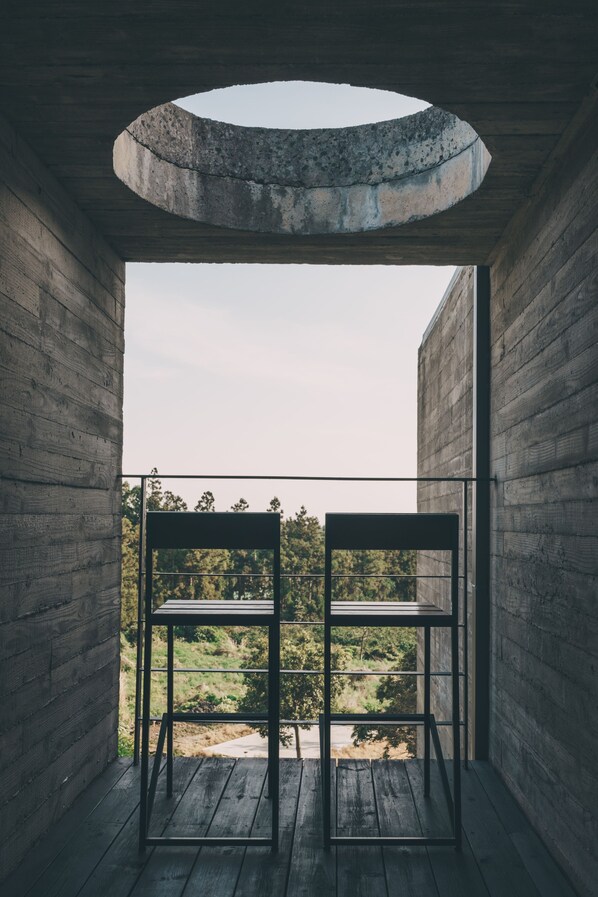 A balcony with a circular skylight, wooden floor, and two metal chairs. - Jeju Stay Biuda (Seogwipo)