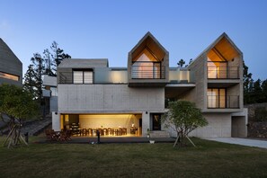 A modern two-story house with a flat roof, large windows, and a balcony. - Jeju Stay Biuda (Seogwipo)