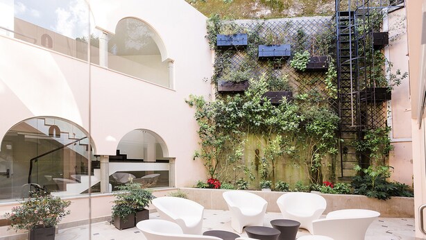 Un patio con sillas blancas, una escalera de incendios y plantas en macetas.