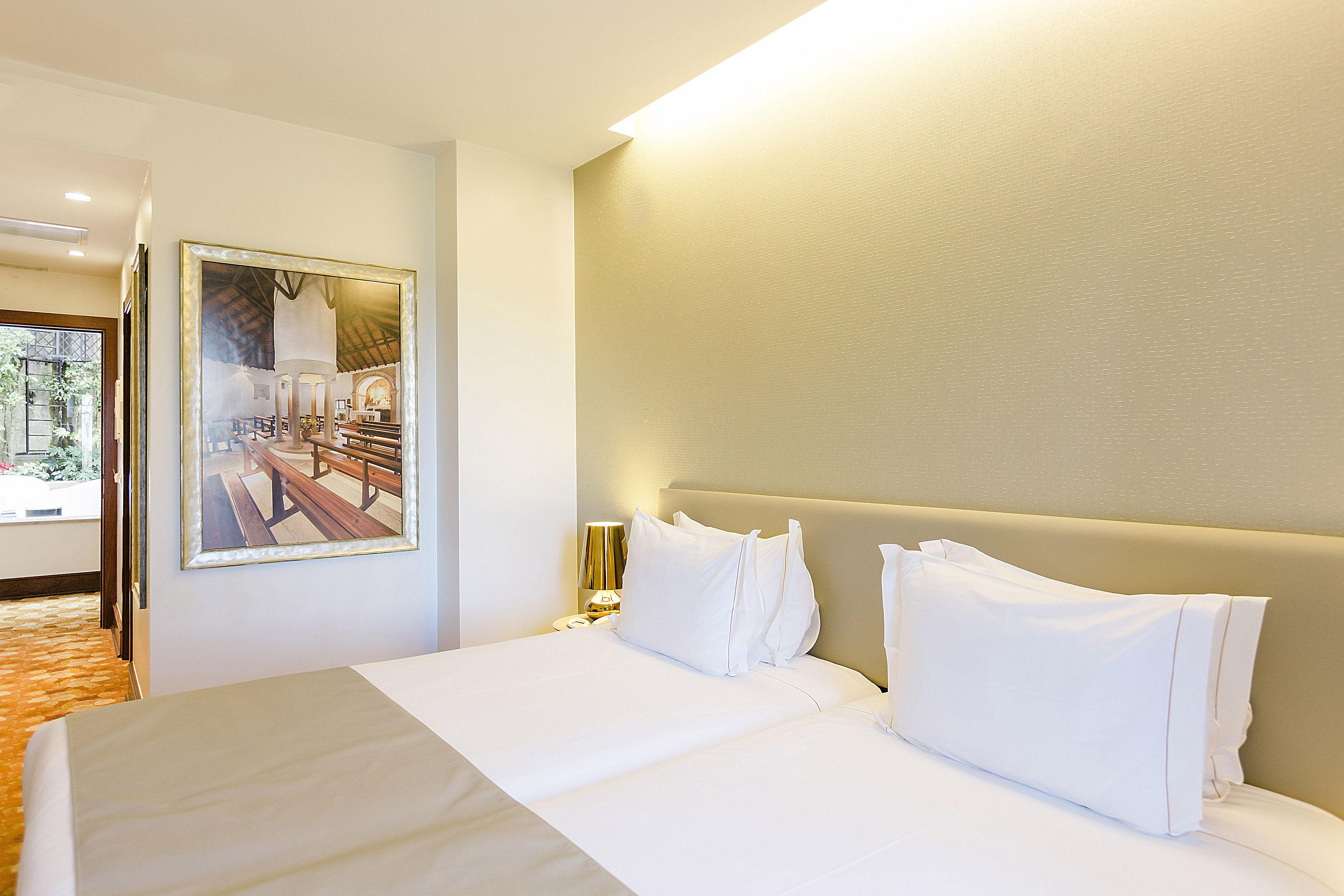 A hotel room with a large bed, a nightstand, a lamp, and a framed picture on the wall.