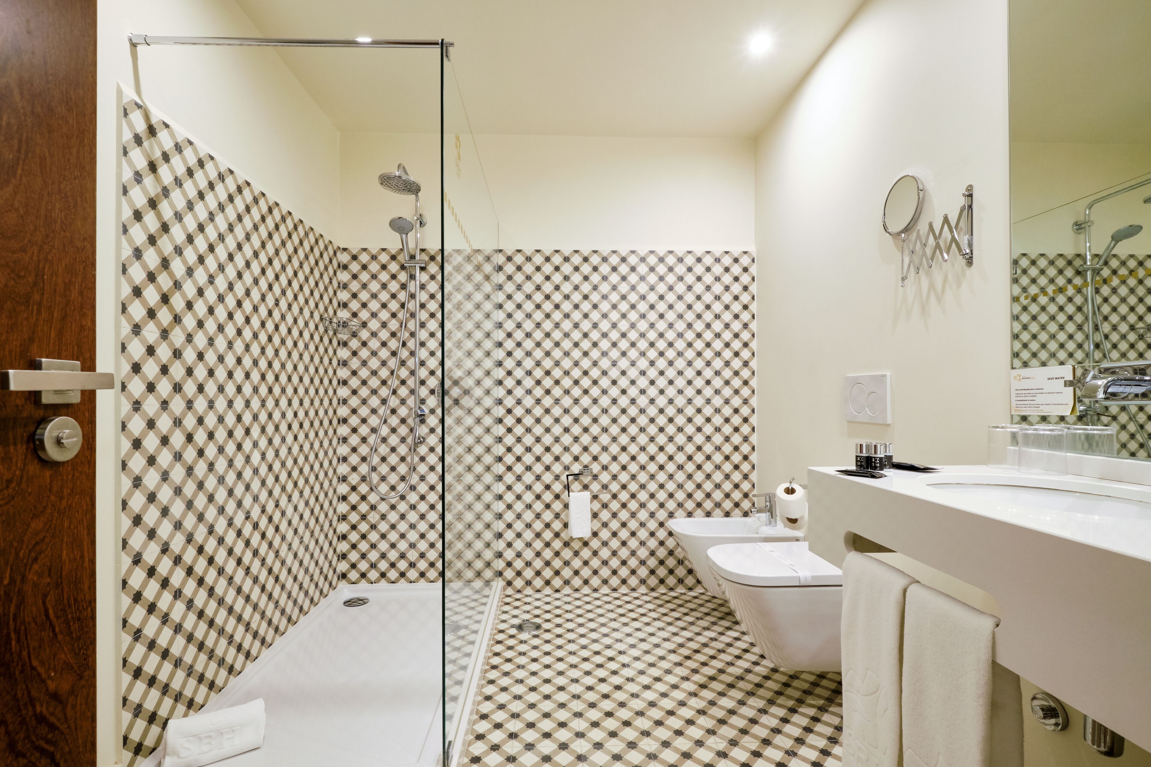Un bagno con pavimento a scacchi, box doccia in vetro, WC e lavandino con specchio.