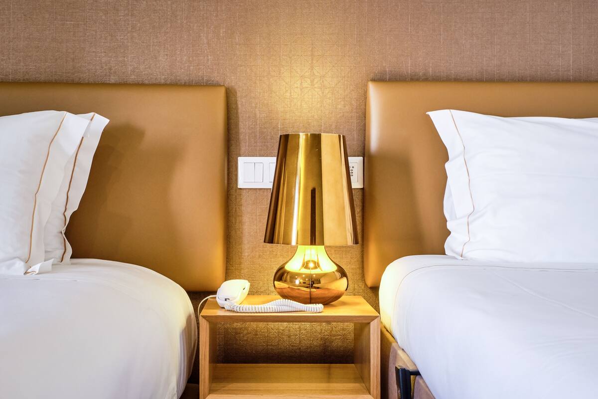 A hotel room with two beds, a bedside lamp, and a phone on the nightstand.