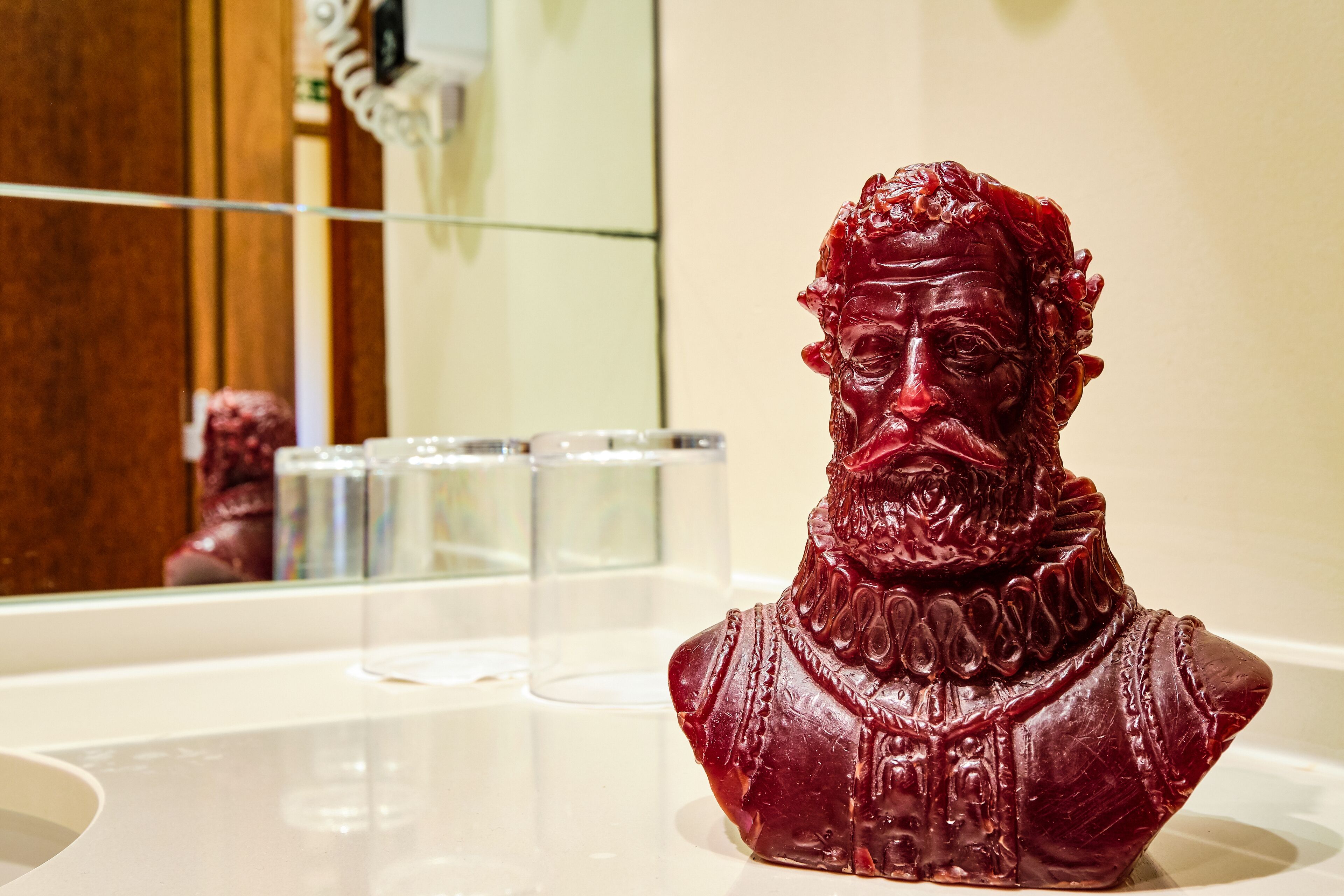 A bust sculpture on a white countertop in a bathroom.