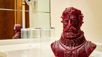 A bust sculpture on a white countertop in a bathroom.