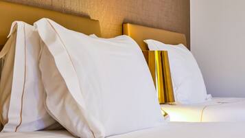A neatly made bed with white linens and a gold headboard.