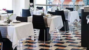 Interior de restaurante con mesas dispuestas para comer, suelo con diseño y pared decorativa con arcos.